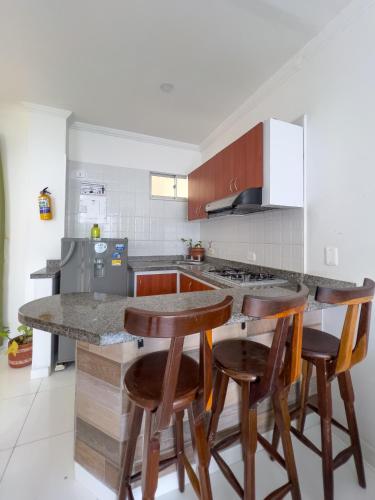 a kitchen with wooden stools and a counter top at Apartamentos Playa Rodadero in Santa Marta