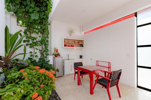 a red table and chairs in a room with plants at Bali Ginger Suites & Villa in Seminyak