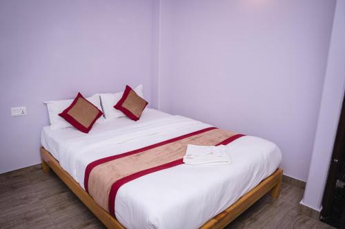 una camera da letto con un letto con lenzuola bianche e cuscini rossi di Hotel sunrise heaven a Pokhara
