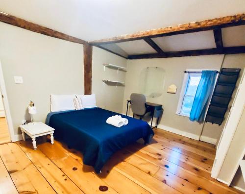 a bedroom with a blue bed and a wooden floor at Rustic Colonial Home with Private Rooms in Waterbury