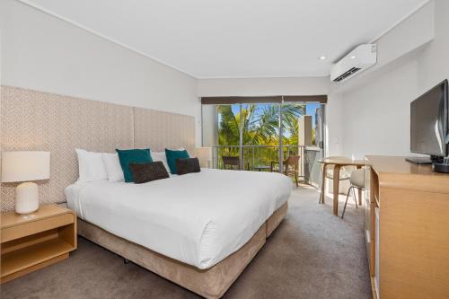 ein Schlafzimmer mit einem großen weißen Bett und einem TV in der Unterkunft Bells Blvd Resort & Spa Apartments - Holiday Management in Kingscliff