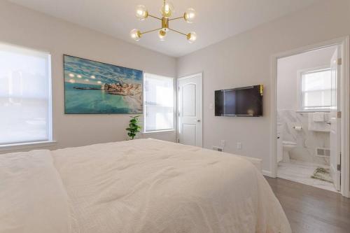 a white bedroom with a bed and a flat screen tv at Beautiful 3bedroom apartment in Elizabeth