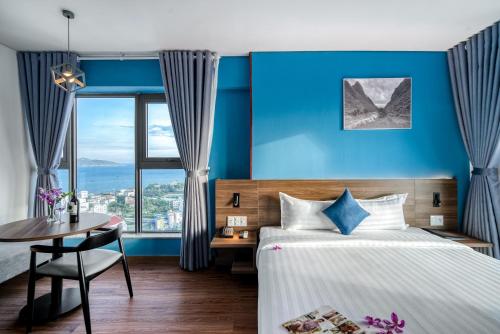 a bedroom with blue walls and a bed and a table at TK Nha Trang Hotel in Nha Trang