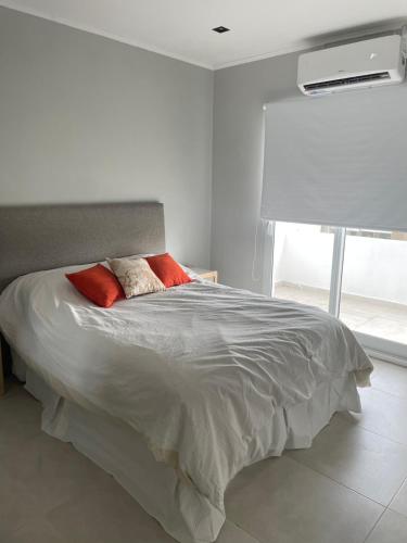 ein Schlafzimmer mit einem Bett mit zwei roten Kissen in der Unterkunft Temporarios Chaco in Presidencia Roque Sáenz Peña