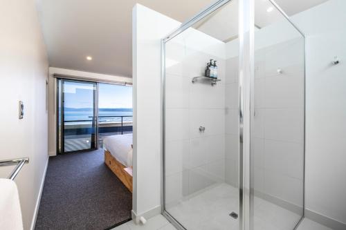 um chuveiro de vidro num quarto com uma cama em Footprints 1 em Coles Bay