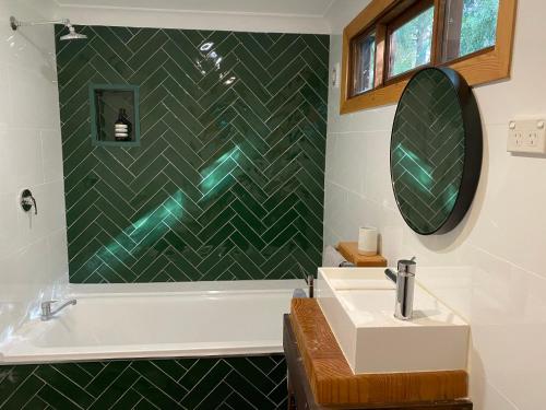 a bathroom with a sink and a tub and a mirror at Crabapple Cabin in Bowral