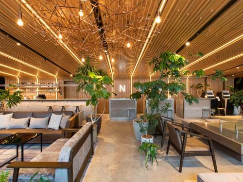 eine Lobby mit Sofas, Tischen und Topfpflanzen in der Unterkunft The Royal Park Canvas - Sapporo Odori Park in Sapporo