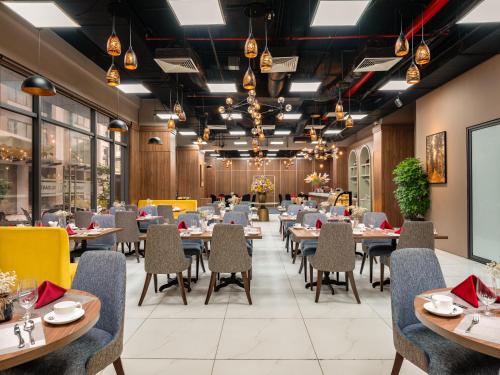 a dining room with tables and chairs and windows at Nesta Hotel & Spa in Hanoi