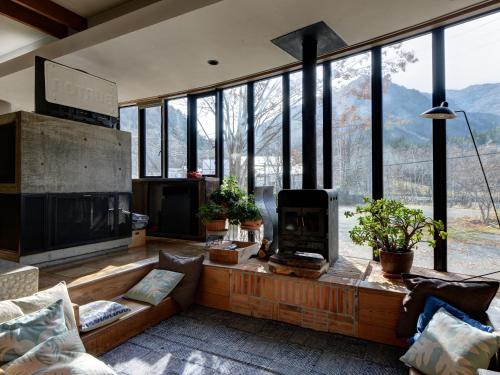 a living room with a fireplace and a large window at the Kinta Naeba in Yuzawa
