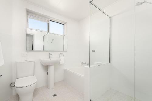 a white bathroom with a toilet and a sink at Dutchies Motel Nelson Bay & Dutchmans Beach Apartments in Nelson Bay