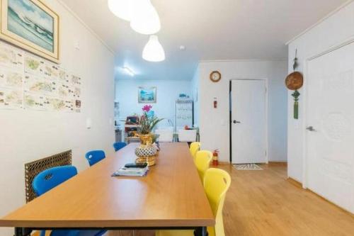 a conference room with a wooden table and yellow chairs at Good Stay Itaewon in Seoul