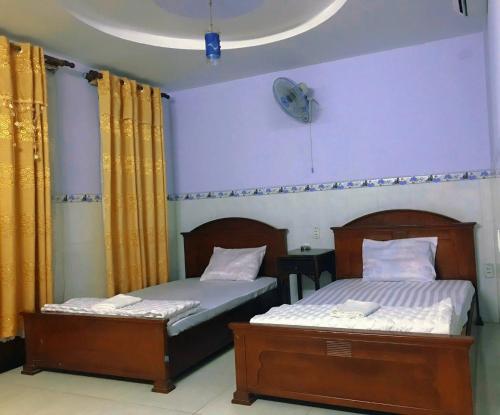 2 camas individuales en un dormitorio con un reloj en la pared en Phúc Lộc Thọ Hotel, en Ho Chi Minh