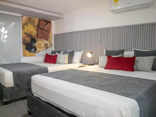 two beds in a hotel room with red pillows at Hotel velero in Roldanillo