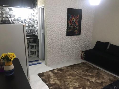 ein Wohnzimmer mit einem schwarzen Sofa und einem Gemälde an der Wand in der Unterkunft Flat Bangalô in Cabo Frio