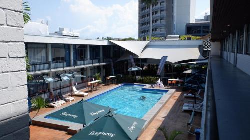 a swimming pool on top of a building with umbrellas at The Cavenagh in Darwin