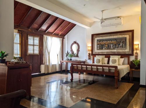 een woonkamer met een bank en een schilderij aan de muur bij La Maison de Bitasta in Pondicherry