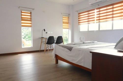 a white bedroom with a bed and two windows at Brand New Home in Cebu City with 3 Large Bedrooms! in Cebu City