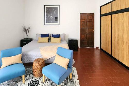a bedroom with a bed and two blue chairs at Preciosa Habitación cercana a Jardines in Querétaro