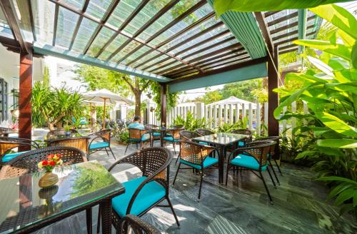 an outdoor patio with tables and chairs and a pergola at The Nam An Villa Hoi An in Hoi An