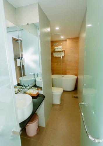 a bathroom with a sink and a toilet and a mirror at Dezon Hotel in Quy Nhon