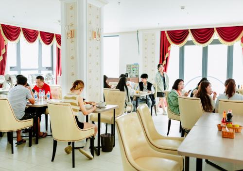 un grupo de personas sentadas en mesas en un restaurante en Dezon Hotel en Quy Nhon