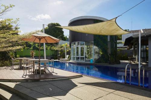 a pool with a table and an umbrella next to a building at The View Villa 2 - 2br Minimalist Villa in Uluwatu in Uluwatu