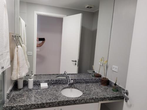 ein Badezimmer mit einem Waschbecken und einem großen Spiegel in der Unterkunft Pajuçara (Beira-mar). Melhor Localização e Conforto. in Maceió