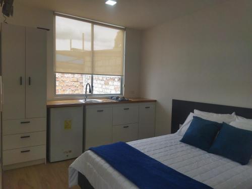 a bedroom with a bed and a sink and a window at ROZA apartaments & suits in Loja