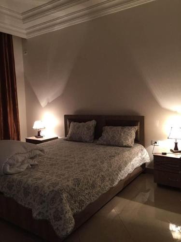 a bedroom with a bed with two lamps on it at un nouveau appartement avec un parking sur place in La Marsa