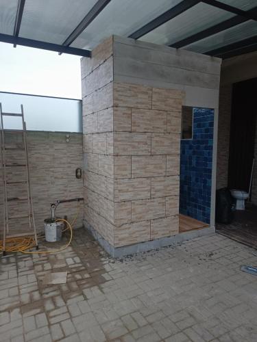 a brick wall with a shower in a room at Apartamento completo 1 quarto in Palhoça