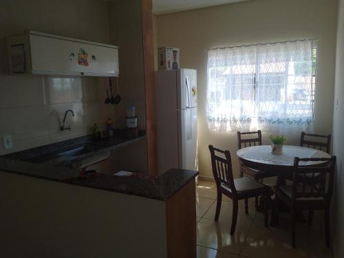 eine Küche mit einem Tisch und einem weißen Kühlschrank in der Unterkunft Bem estar in Aparecida
