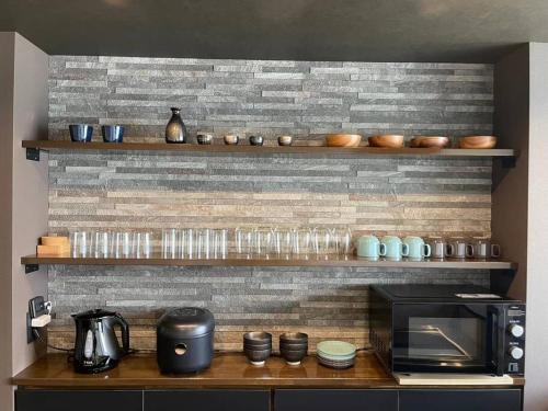 a kitchen with a counter with a microwave and some cups at 壇ノ浦ハウス in Shimonoseki