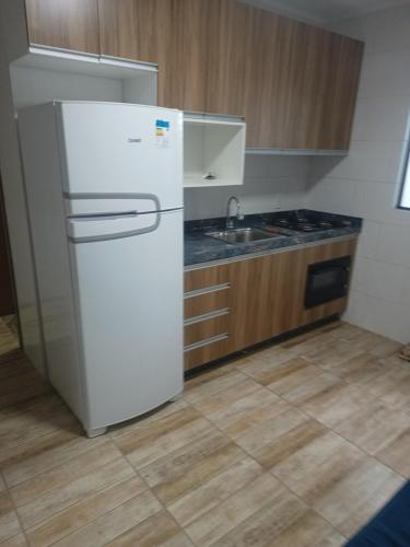een keuken met een witte koelkast en een wastafel bij Apartamento completo praia do sonho in Palhoça