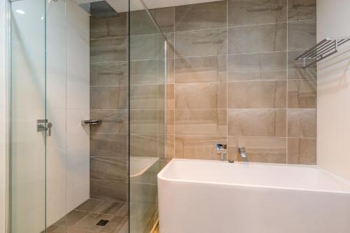 uma casa de banho com um chuveiro, uma banheira e um lavatório. em Ishtar Apartment 10- Water Views em Huskisson