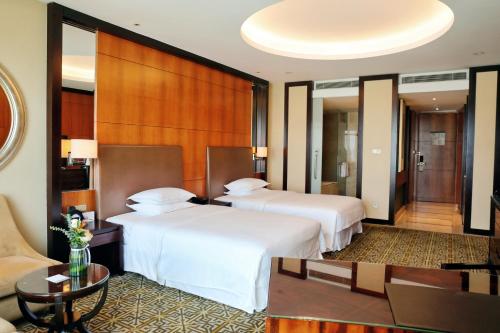 a hotel room with two beds and a couch at Sheraton Jinan Hotel in Jinan