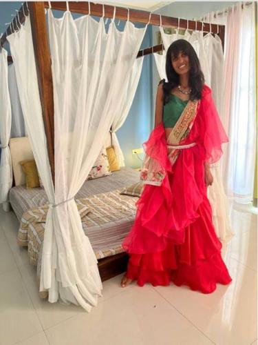 a woman in a red dress standing next to a bed at Monday Blues in Bhilwara
