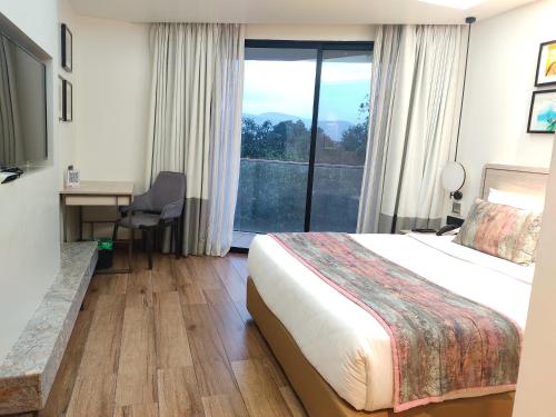 a hotel room with a bed and a large window at Regenta SGS Greenotel - Lonavala in Lonavala