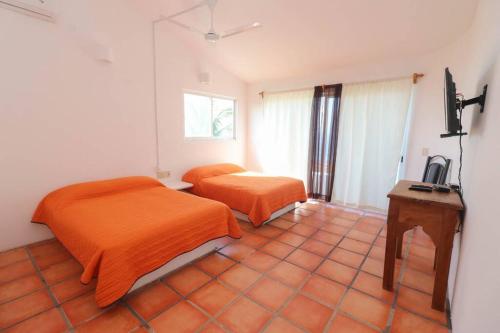 a bedroom with two beds and a table and a television at Tehuana l House, Ocean view, pool. in Tangolunda