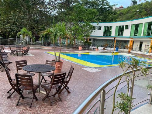 a patio with a table and chairs next to a pool at Hotel la cascada cristalina in Melgar