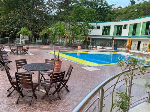 a patio with a table and chairs next to a pool at Hotel Cascada Cristalina in Melgar