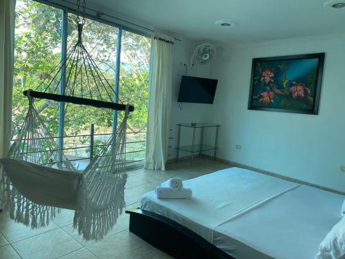 a bedroom with a swinging bed and a large window at Hotel la cascada cristalina in Melgar