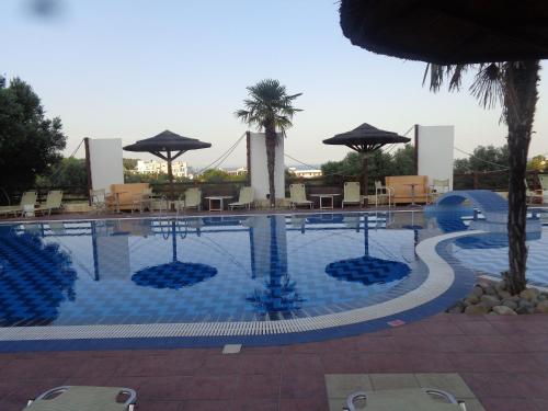 a large swimming pool with chairs and umbrellas at Angela Hotel in Agia Marina Aegina