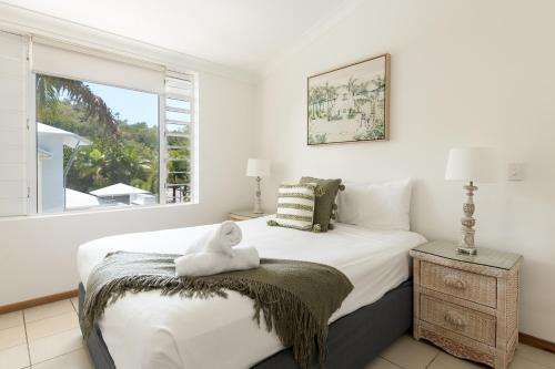 a bedroom with a bed with a teddy bear on a blanket at Verandahs Boutique Apartments in Port Douglas