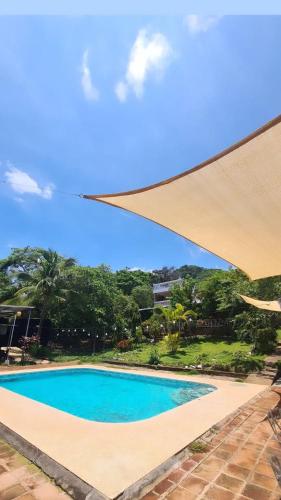 a blue swimming pool with a large umbrella at Jaco Mizata Beach and River in La Libertad