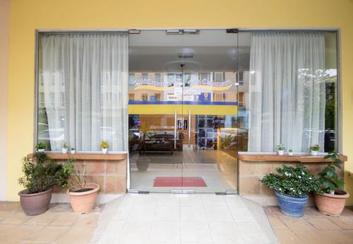 a glass door of a building with potted plants at Sun Inns Hotel Kota Damansara Near Hospital Sungai Buloh in Kota Damansara