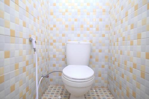 La salle de bains est pourvue de toilettes blanches et de murs carrelés. dans l'établissement RedDoorz Syariah @ Jalan Dieng Wonosobo 2, à Garung