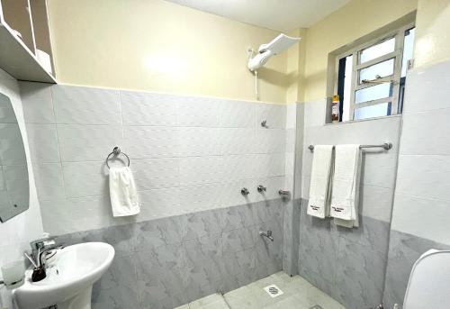 a white bathroom with a sink and a toilet at Naka Executive Suites With Balcony, Amazing Lake Nakuru View, GYM in Nakuru
