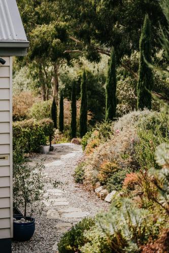 a garden path with trees and bushes next to a house at Ascona - Hepburn Springs Daylesford in Hepburn Springs