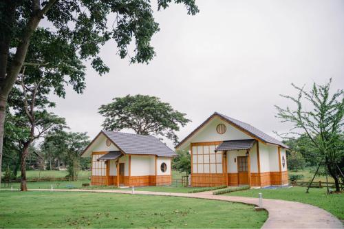 two small buildings in a park with trees at บ้านเรียวชิน น่าน りょうしん in Nan