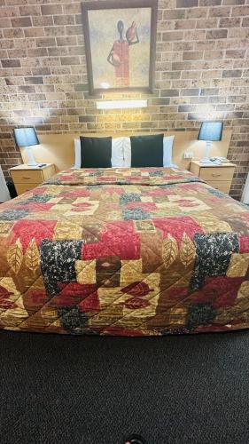 a large bed in a room with a brick wall at Golden Grain Motor Inn in Tamworth